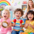 Children playing musical instruments in a colorful music class with their mothers. The group of toddlers is smiling, holding instruments like tambourines, maracas, and rhythm sticks.